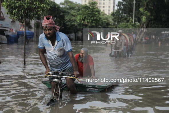 A rickshaw puller is wading through a waterlogged street after a heavy downpour in Dhaka, Bangladesh, on July 12, 2024. 