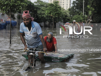 A rickshaw puller is wading through a waterlogged street after a heavy downpour in Dhaka, Bangladesh, on July 12, 2024. (