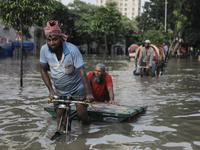 A rickshaw puller is wading through a waterlogged street after a heavy downpour in Dhaka, Bangladesh, on July 12, 2024. (