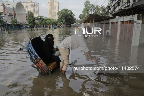 A rickshaw puller is wading through a waterlogged street after a heavy downpour in Dhaka, Bangladesh, on July 12, 2024. 