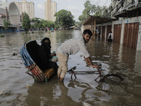 A rickshaw puller is wading through a waterlogged street after a heavy downpour in Dhaka, Bangladesh, on July 12, 2024. (