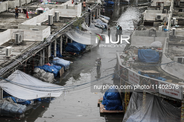 A street vendor is wading through a waterlogged market while carrying some goods on his shoulder to a dry place after a heavy downpour in Dh...