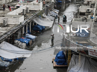 A street vendor is wading through a waterlogged market while carrying some goods on his shoulder to a dry place after a heavy downpour in Dh...