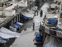 A street vendor is wading through a waterlogged market while carrying some goods on his shoulder to a dry place after a heavy downpour in Dh...