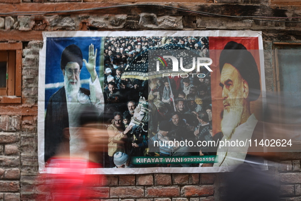 Shiite Muslim mourners are walking past a poster showing supreme leader, Ayatollah Ali Khamenei (L) and the founder of Iran's Islamic Republ...