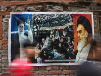 Shiite Muslim mourners are walking past a poster showing supreme leader, Ayatollah Ali Khamenei (L) and the founder of Iran's Islamic Republ...