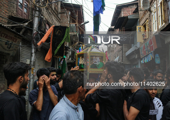 Kashmiri mourners are touching a glass case containing a copy of the Koran during a Muharram procession on the fifth day of Ashura, in Srina...