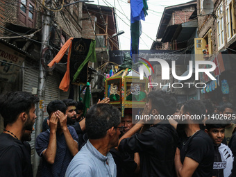 Kashmiri mourners are touching a glass case containing a copy of the Koran during a Muharram procession on the fifth day of Ashura, in Srina...