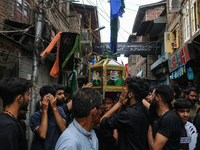 Kashmiri mourners are touching a glass case containing a copy of the Koran during a Muharram procession on the fifth day of Ashura, in Srina...