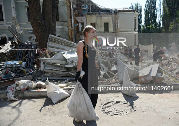 A girl is holding a sack as volunteers are helping clean the premises of the Ohmatdyt National Specialized Children's Hospital destroyed by...