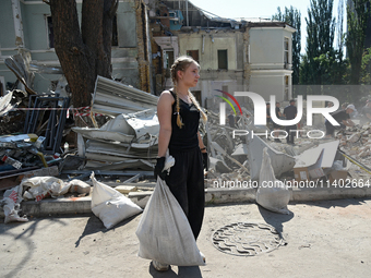 A girl is holding a sack as volunteers are helping clean the premises of the Ohmatdyt National Specialized Children's Hospital destroyed by...