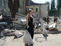 A girl is holding a sack as volunteers are helping clean the premises of the Ohmatdyt National Specialized Children's Hospital destroyed by...