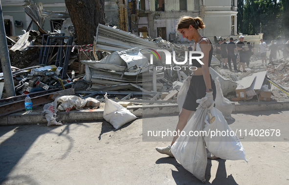 A girl is carrying sacks as volunteers are helping clean the premises of the Ohmatdyt National Specialized Children's Hospital destroyed by...