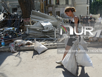 A girl is carrying sacks as volunteers are helping clean the premises of the Ohmatdyt National Specialized Children's Hospital destroyed by...