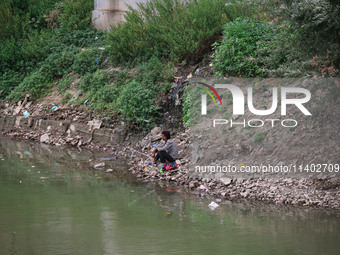 A man is catching fish on the banks of River Jhelum in Srinagar, Jammu and Kashmir, on July 12, 2024. (