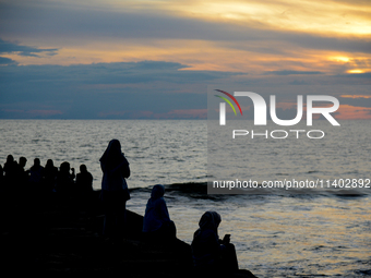 People are enjoying the sunset at Padang Beach in West Sumatra, Indonesia, on July 12, 2024. (