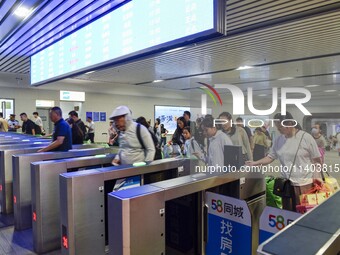 Passengers are passing through the gate at the exit of the East high-speed railway station in Huai'an city, East China's Jiangsu province, o...