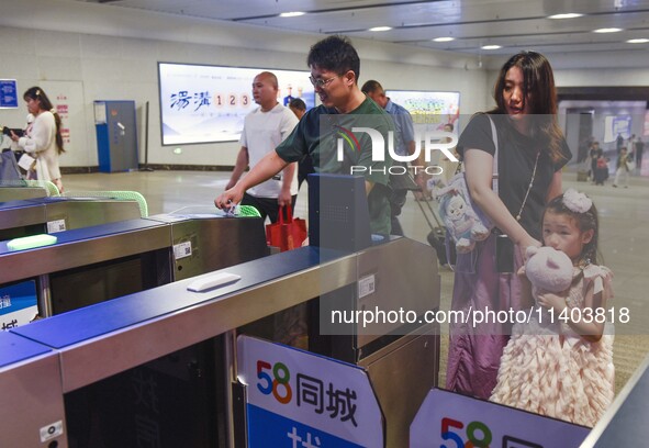 Passengers are passing through the gate at the exit of the East high-speed railway station in Huai'an city, East China's Jiangsu province, o...