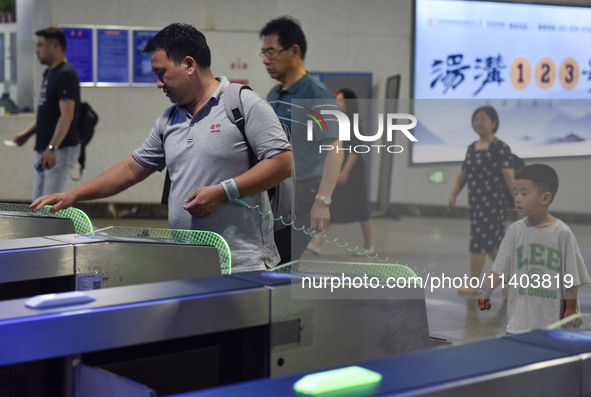 Passengers are passing through the gate at the exit of the East high-speed railway station in Huai'an city, East China's Jiangsu province, o...