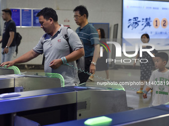 Passengers are passing through the gate at the exit of the East high-speed railway station in Huai'an city, East China's Jiangsu province, o...