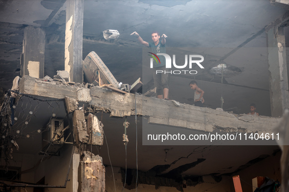 Palestinians are assessing the damage following an Israeli strike in the Nuseirat refugee camp in the central Gaza Strip on July 13, 2024, a...