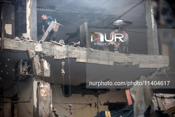 Palestinians are assessing the damage following an Israeli strike in the Nuseirat refugee camp in the central Gaza Strip on July 13, 2024, a...