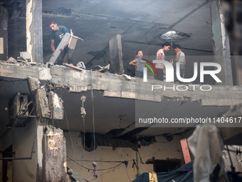 Palestinians are assessing the damage following an Israeli strike in the Nuseirat refugee camp in the central Gaza Strip on July 13, 2024, a...