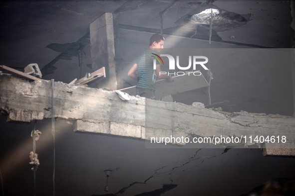 A Palestinian young man is checking the damage in a house hit by Israeli bombardment in Nuseirat, in the central Gaza Strip, on July 13, 202...