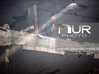 A Palestinian young man is checking the damage in a house hit by Israeli bombardment in Nuseirat, in the central Gaza Strip, on July 13, 202...