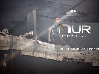 A Palestinian young man is checking the damage in a house hit by Israeli bombardment in Nuseirat, in the central Gaza Strip, on July 13, 202...