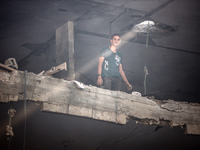 A Palestinian young man is checking the damage in a house hit by Israeli bombardment in Nuseirat, in the central Gaza Strip, on July 13, 202...