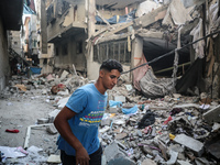 A Palestinian young man is checking the damage in a house hit by Israeli bombardment in Nuseirat, in the central Gaza Strip, on July 13, 202...