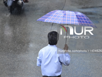 A pedestrian is traveling in the heavy rainfall with an umbrella in Kirtipur, Kathmandu, Nepal, on July 12, 2024. (