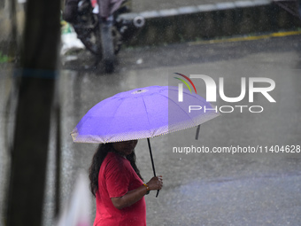 A pedestrian is traveling in the heavy rainfall with an umbrella in Kirtipur, Kathmandu, Nepal, on July 12, 2024. (