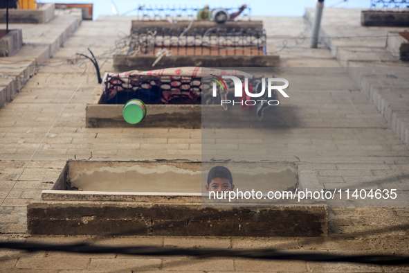 A Palestinian boy is looking out the window of his house in the Nuseirat refugee camp in the central Gaza Strip on July 13, 2024, amid the o...