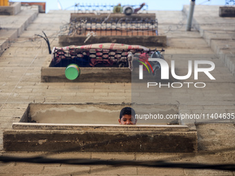 A Palestinian boy is looking out the window of his house in the Nuseirat refugee camp in the central Gaza Strip on July 13, 2024, amid the o...