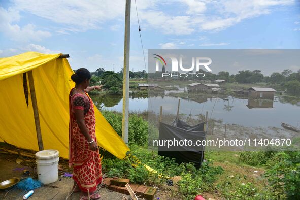 A flood-affected woman is looking at her partially submerged house after heavy rains in Nagaon District of Assam, India, on July 13, 2024. 