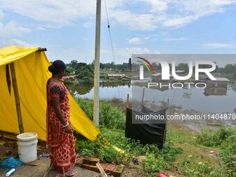 A flood-affected woman is looking at her partially submerged house after heavy rains in Nagaon District of Assam, India, on July 13, 2024. (