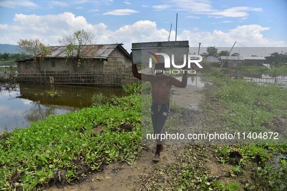 A villager is transporting his belongings from his partially submerged house in the flood-affected village of Jakhalabandha in Nagaon Distri...