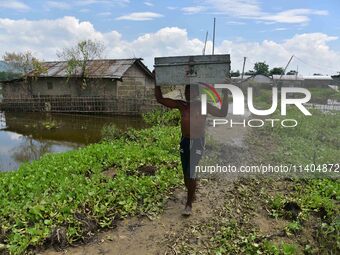 A villager is transporting his belongings from his partially submerged house in the flood-affected village of Jakhalabandha in Nagaon Distri...