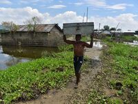 A villager is transporting his belongings from his partially submerged house in the flood-affected village of Jakhalabandha in Nagaon Distri...