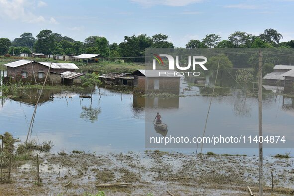 A man is rowing a boat near a partially submerged house after heavy rains in Nagaon District of Assam, India, on July 13, 2024. 