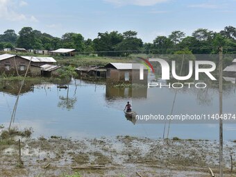 A man is rowing a boat near a partially submerged house after heavy rains in Nagaon District of Assam, India, on July 13, 2024. (