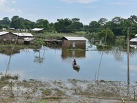 A man is rowing a boat near a partially submerged house after heavy rains in Nagaon District of Assam, India, on July 13, 2024. (