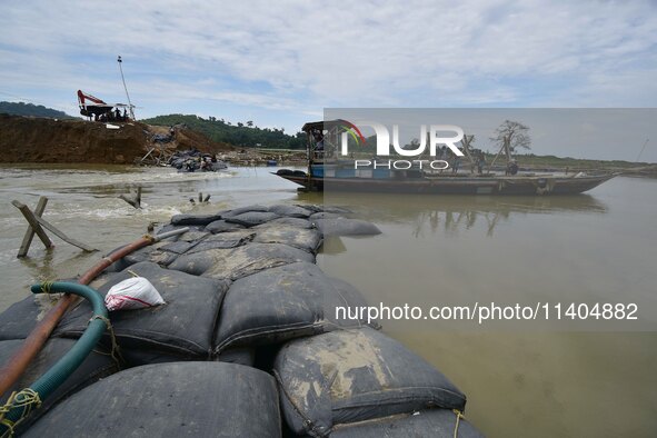 Indian laborers are piling up mega Geo bags as they are restoring an embankment that is damaged by flood water, in Hatimura, Nagaon District...