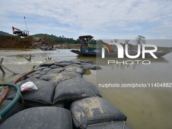 Indian laborers are piling up mega Geo bags as they are restoring an embankment that is damaged by flood water, in Hatimura, Nagaon District...