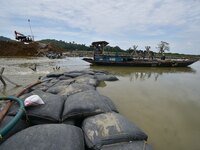 Indian laborers are piling up mega Geo bags as they are restoring an embankment that is damaged by flood water, in Hatimura, Nagaon District...