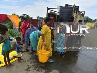 Flood-affected villagers are collecting drinking water from a relief camp conducted by the Public Health Centre (PHC) in Jakhalabandha, Naga...