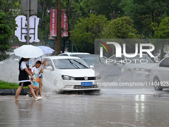 Citizens are traveling on a flooded road in Neijiang, Sichuan province, China, on July 13, 2024. (