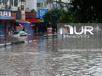 Vehicles are being trapped by a flooded road in Neijiang, China, on July 13, 2024. (